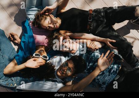 Directly above shot of cheerful young male and female friends lying down on floor in sunlight Stock Photo