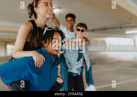 Happy curly hair young woman piggybacking female friend in parking garage Stock Photo
