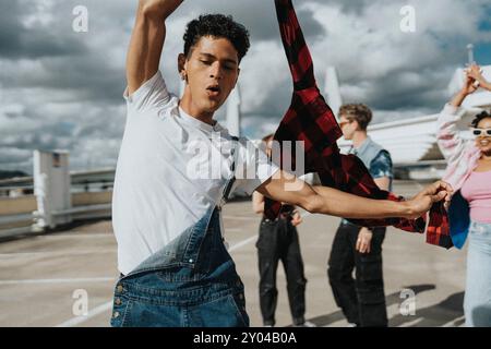 Carefree young man holding jacket and dancing with friends in parking lot Stock Photo