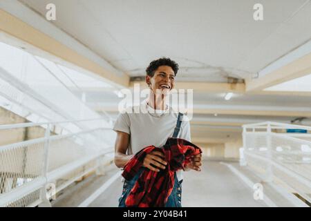 Cheerful young man in bib overalls holding jacket and walking in parking garage Stock Photo