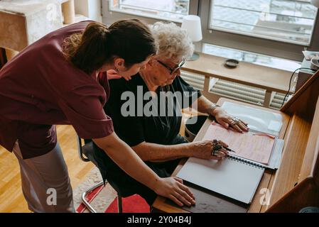 High angle view of female healthcare worker assisting senior woman doing paperwork at desk in apartment Stock Photo