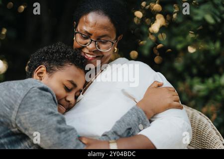 Curly hair boy embracing grandmother sitting at back yard Stock Photo