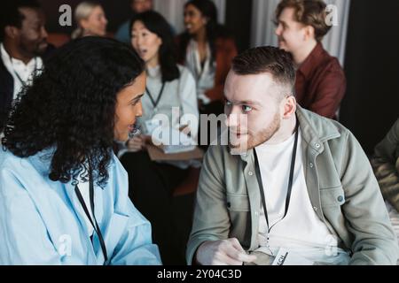 Male and female business delegates discussing while sitting in seminar at convention center Stock Photo