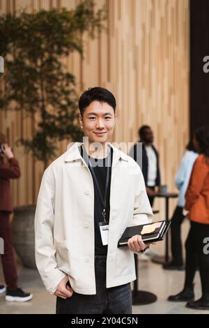 Portrait of smiling young male entrepreneur holding diary at seminar Stock Photo