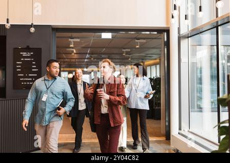Male and female business delegates discussing while walking at convention center Stock Photo