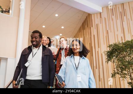 Smiling male and female entrepreneurs discussing while moving down from staircase at convention center Stock Photo