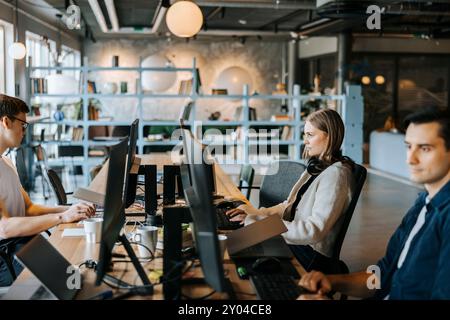 Young male and female programmer working while sitting at desk in office Stock Photo