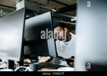 Tired male businessman with head in hand looking at computer screen in tech startup office Stock Photo