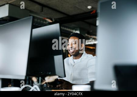 Smiling programmer working on desktop PC at tech startup office Stock Photo