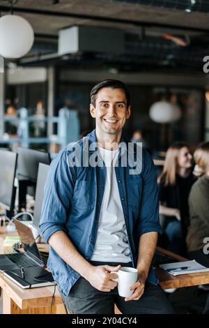 Portrait of smiling male entrepreneur with coffee cup in workplace Stock Photo