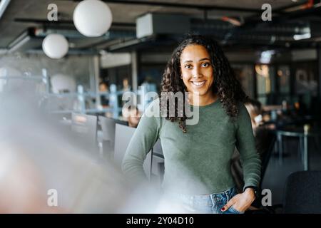 Portrait of happy female programmer with hands in pockets standing in tech startup office Stock Photo