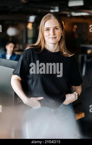Portrait of female tech programmer standing with hands in pockets at office Stock Photo