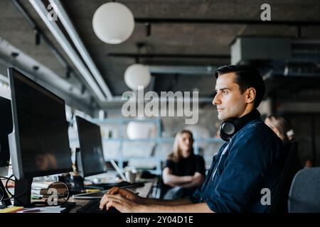 Side view of male tech programmer with headphones coding at office Stock Photo