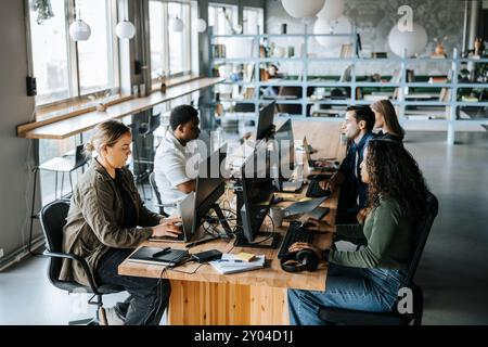 Male and female entrepreneurs sitting at desk and working at coworking office Stock Photo