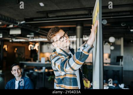 Businessman sticking adhesive notes on whiteboard in office Stock Photo
