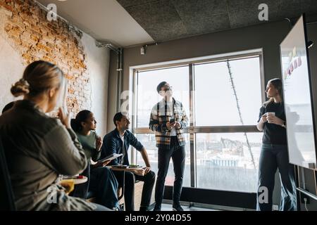 Young female programmer taking team meeting in tech startup office Stock Photo