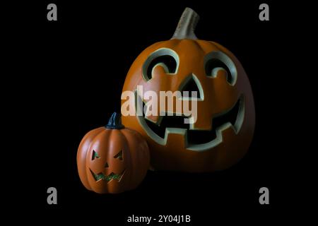 This image features two carved pumpkins, both with smiling faces, isolated on a black background. Stock Photo