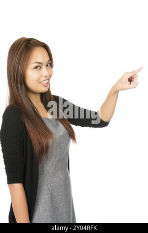 Side profile of gorgeous Asian woman in black sweater with light brown hair, arm extended index finger pressing imaginary button looking at camera. Th Stock Photo