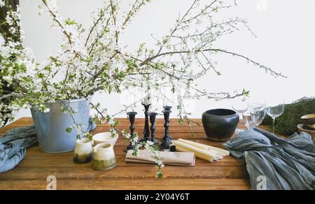 Various colorful flowers and green plants in buckets placed on wooden table in light white room Stock Photo