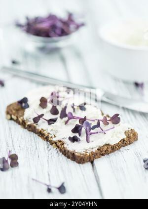 An old wooden table with healthy food (slice of bread, cream cheese and fresh cutted cress), selective focus Stock Photo