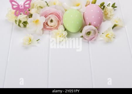 Easter eggs with ranunculus flowers on white wooden background Stock Photo