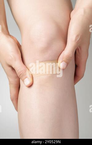 Woman putting an adhesive bandage on her leg Stock Photo