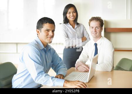 A latino businessman leads a diverse team of business people including an attractive Asian woman and caucasian male Stock Photo