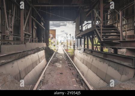 Abandoned industrial site with dilapidated railway tracks and sturdy metal structures under a cloudy sky, HF4 steelworks, Lost Place, Dampremy, Charle Stock Photo