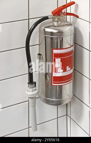 Silver fire extinguisher in building corner Stock Photo