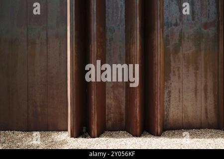 A close-up of an industrial rusted metal wall with large vertical beams, showing the texture and weathering of the surface. Stock Photo