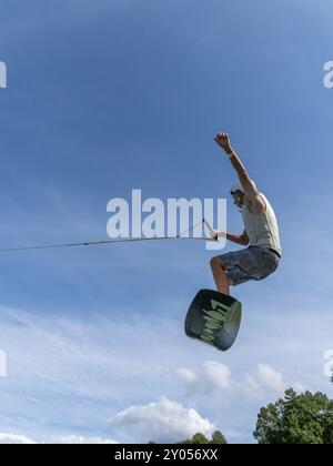 Young man jumping and flying with wakeboard, water sports and water skiing in the wakepark Stock Photo