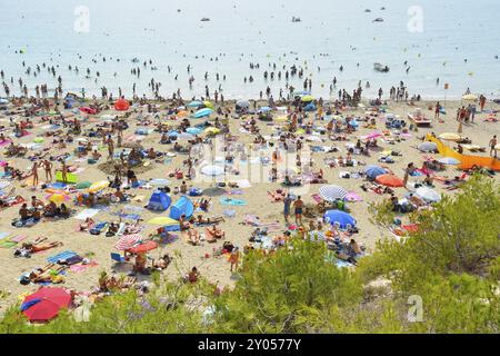 A crowded beach with many people sunbathing and swimming, colorful umbrellas and the sea in the background, Summer, Plage de Sainte Croix, La Couronne Stock Photo