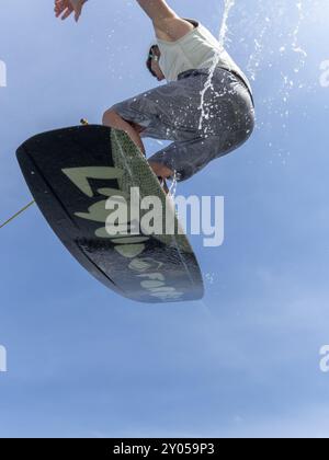 Young man jumping and flying with wakeboard, water sports and water skiing in the wakepark Stock Photo