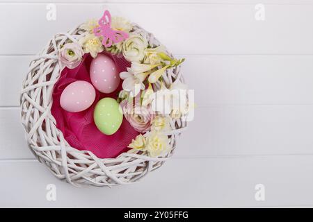 Basket of easter eggs with flowers on white wooden background Stock Photo