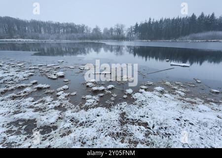 Misty clouded winter morning on lake in forest Stock Photo