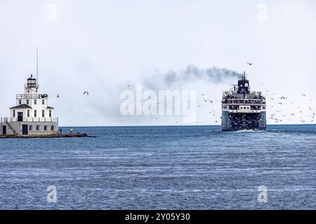 Manitowoc WI USA July 18 2023 : Ludington MI to Manitowoc WI SS Badger People Car Ferry. The ship sails past the lighthouse and leaves the dock in Man Stock Photo