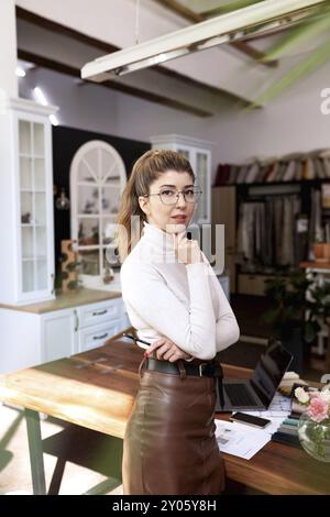 An interior designer at workplace is working on a new project, thinking about decision concideration. Laptop and project plans on the desk. Thinking a Stock Photo
