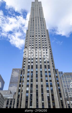 Rockefeller Center building facade, New York City, low angle view during daytime with blue sky and some clouds, reflection on the windows of the build Stock Photo