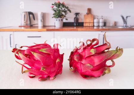 Close-up of whole and cut red dragon fruit on a kitchen table Stock Photo