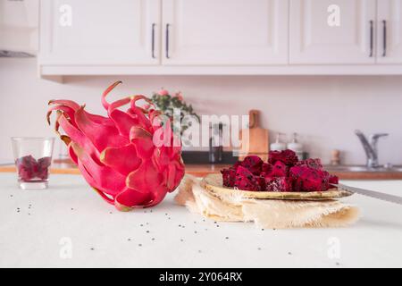 Close-up of whole and cut red dragon fruit on a kitchen table Stock Photo