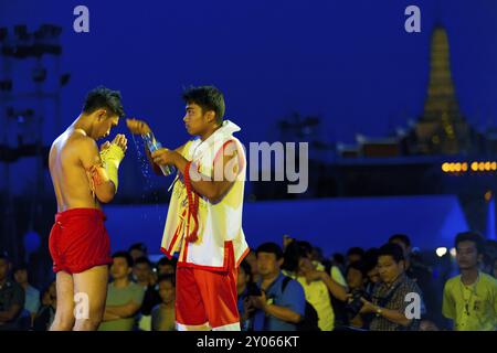 Bangkok, Thailand, April 10, 2007: Trainer pouring water over kickboxer during pre-fight ceremony at outdoor exhibition muay thai kickboxing match at Stock Photo