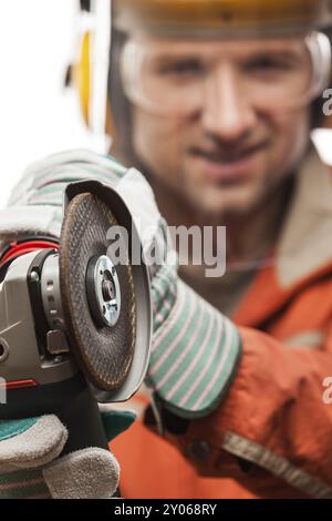 Construction building engineer or manual worker man in safety hardhat helmet hand holding electric angle grinder disk tool white isolated Stock Photo