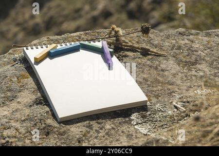 Close-up artwork for the designer. A blank notepad for drawing pastel on which lay an artistic pastel crayons color chalks of purple green blue and ye Stock Photo