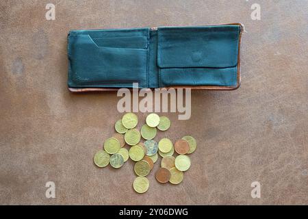 Coins next to a wallet on a brown leather background. Stock Photo