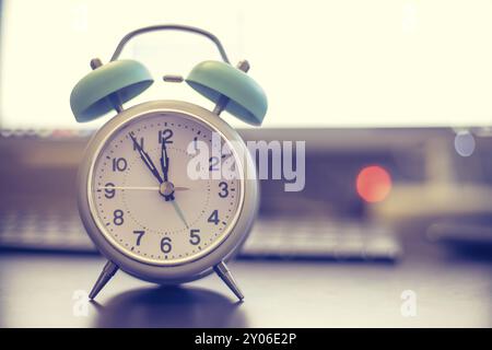 Alarm clock on the desk, office stuff in the blurry background, deadlines and todos Stock Photo