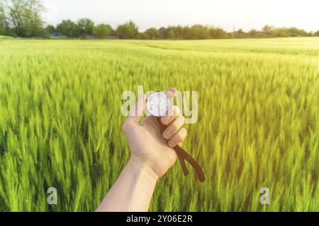 Finding a direction in nature on a wheat field. A man's hand holds a compass Stock Photo