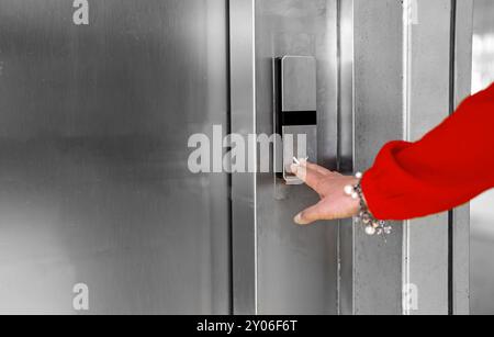 Woman in red dress pressing button inside elevator. Stock Photo