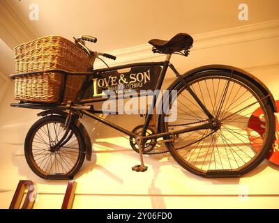 Love and Son family butchers traditional butcher's bike with cargo rack and wicker basket mounted on wall and displayed in Chippenham Museum, Wilshire Stock Photo