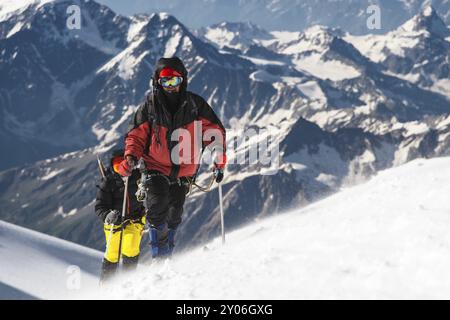 The climber climbs the snow-covered summit. The concept of overcoming difficulties and achieving the goal Stock Photo