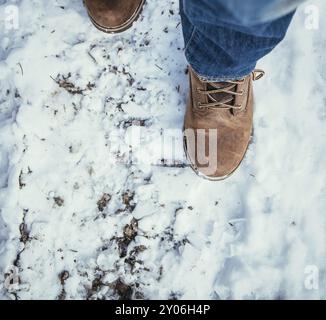 Man in blue jeans is hiking in the wintertime, legs and shoes Stock Photo